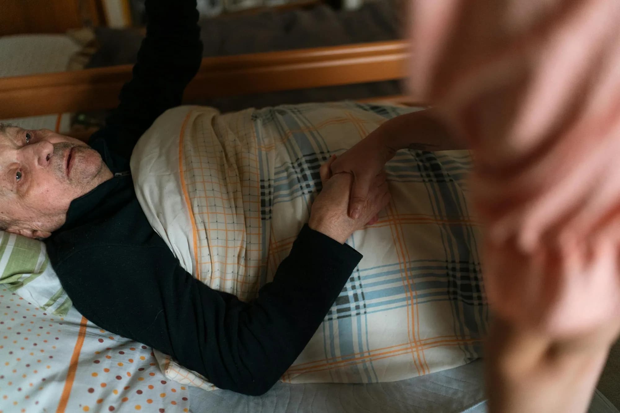 A Polaris Gateway carer holds the hand of an older adult at home, offering quiet reassurance.
